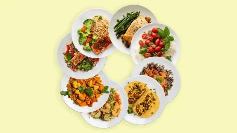 A variety of prepped meals in organized in circular form on a yellow background