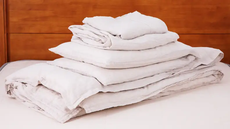 stack of linen sheets on bed