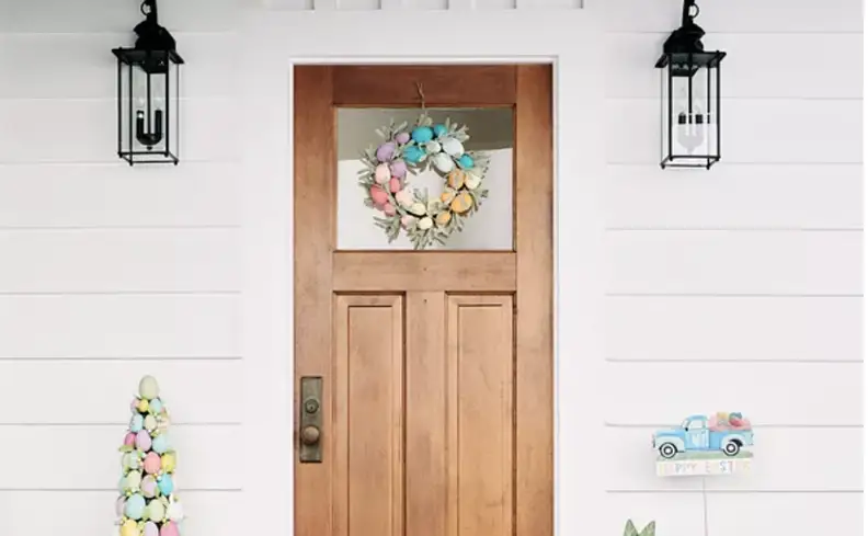 The front door of a home, decorated with an Easter wreath made up of pastel colored eggs.