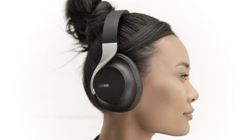 A pair of stylish black headphones with a silver band and ergonomic curves sit on a woman's head