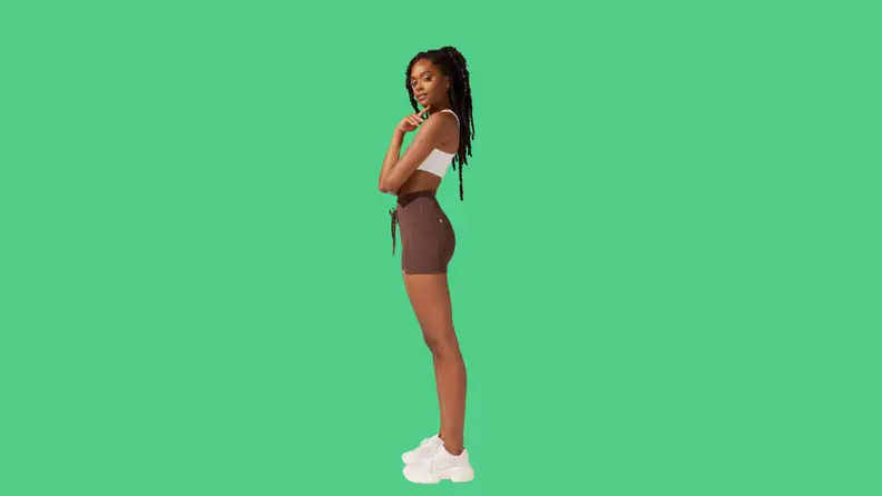 A model wearing brown athletic shorts and a white top.