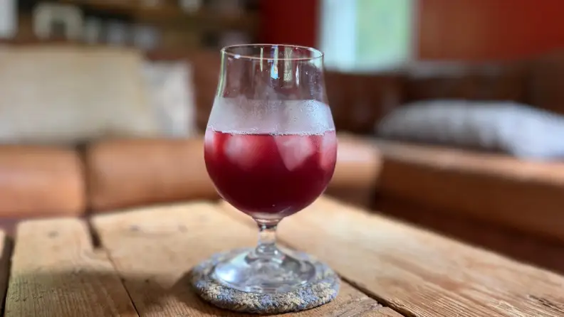 A glass of red liquid on ice in a living room