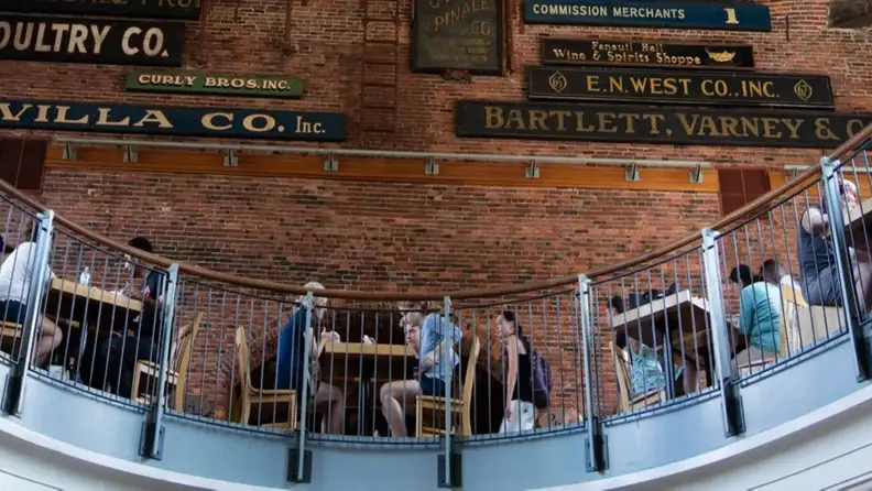 Curved balcony railing beneath historic brick-wall trade signs