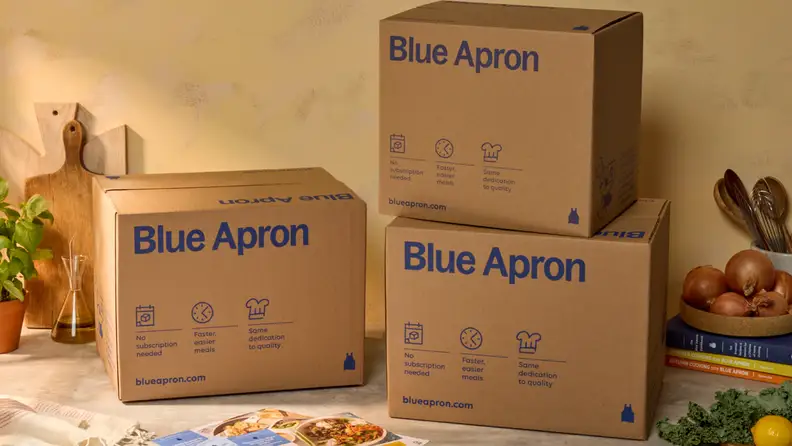 Stacked Blue Apron meal kit boxes displayed on a kitchen counter.