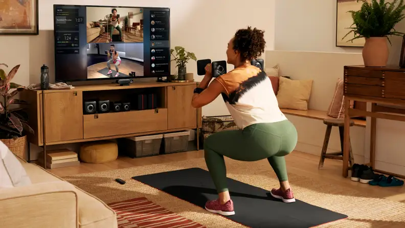 A woman doing squats with the Peloton Guide.