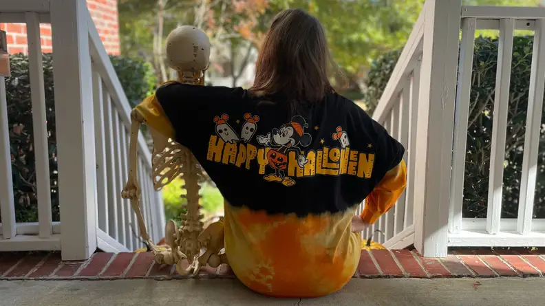 Woman wearing a Mickey Mouse sweatshirt with an arm around a skeleton