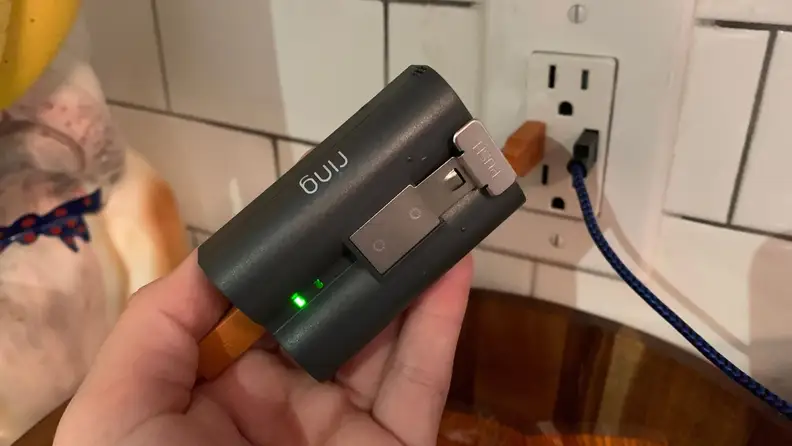 A hand holding a Ring doorbell battery.