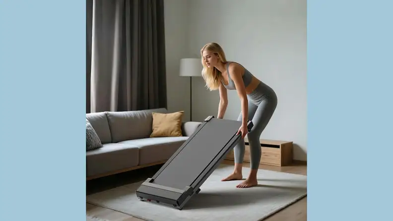 A woman moves a walking pad in a living room