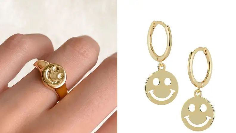 A split of a gold smiley face ring on a hand and gold smiley face earrings on a white background