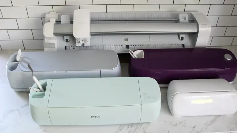A group of variously colored Cricut machines assorted on a white countertop.