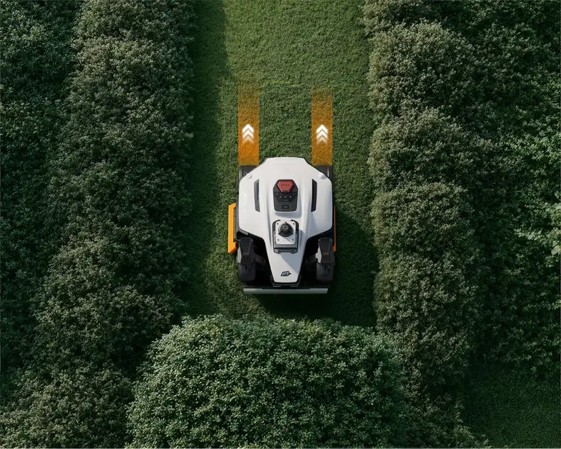 Overhead view of the MAMMOTION LUBA 4 AWD mowing a narrow strip of grass between tall hedges.