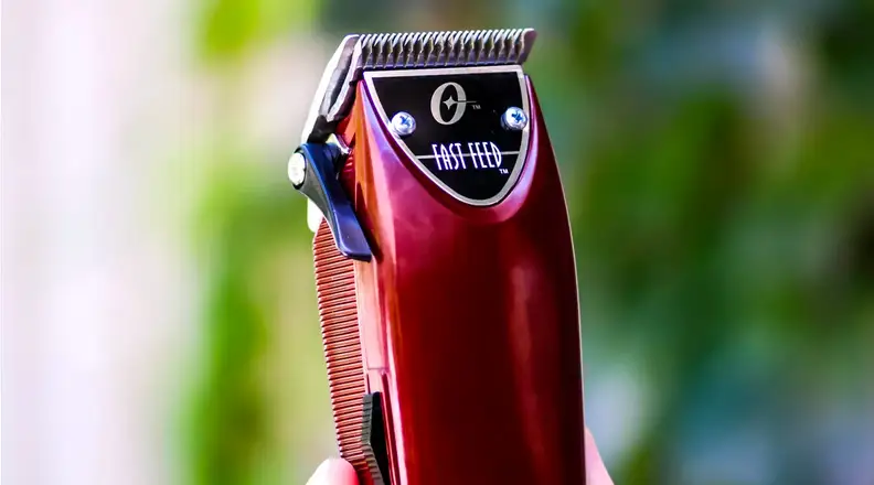 Closeup of a red hair trimmer with tree leaves in the background