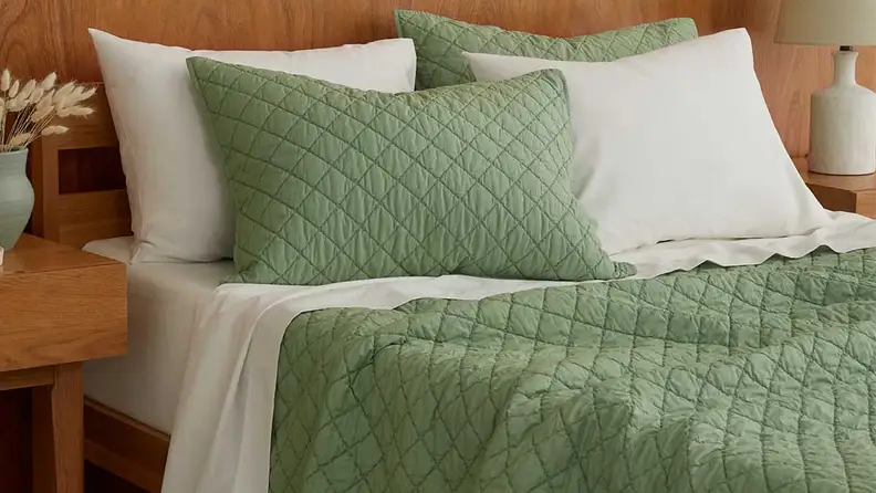 Tuft & Needle Percale Quilted Sham set on a mattress in a bedroom setup.