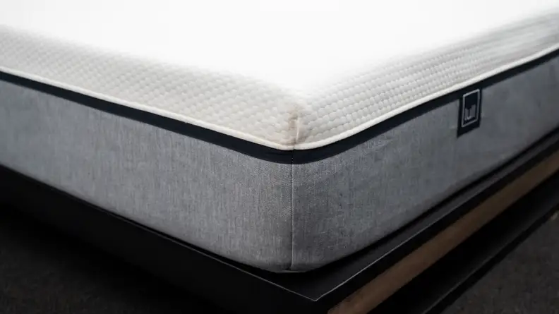 the corner of the lull mattress with a gray bottom fabric and white upper fabric