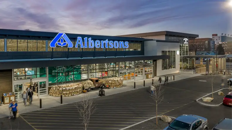 Aerial view of an Albertsons storefront at dusk with lit signage