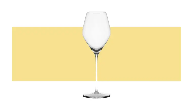 A single tulip-shaped champagne glass on a yellow background.