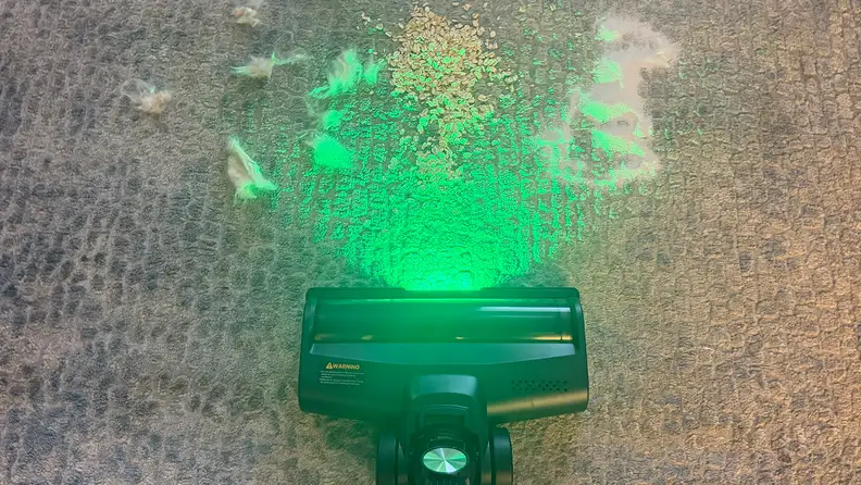 Green LED light emitted from Yaber HP20 cordless vacuum on grey rug.