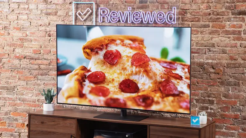 An LG G4 OLED TV on a wood entertainment center with a Reviewed sign above the TV.