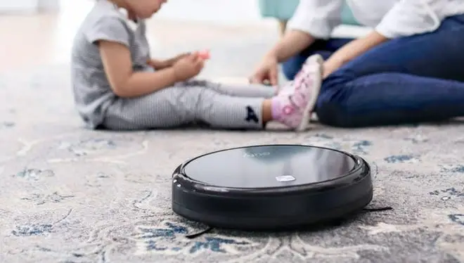 A Eufy 11S robot vacuum cleaning a carpet.
