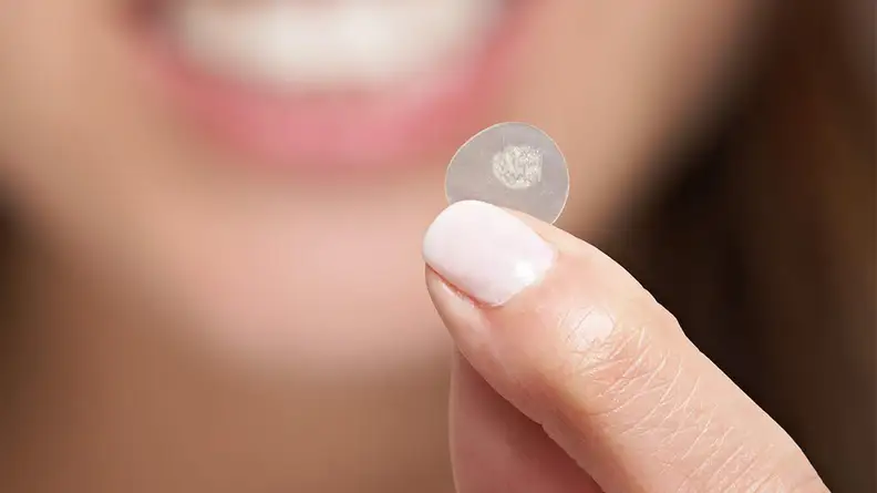 A woman holds a used acne patch.