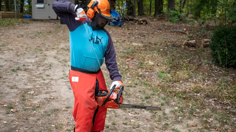 A man in safety gear starts up an Echo chainsaw