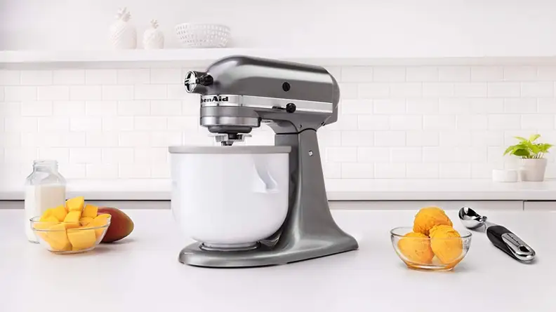 KitchenAid ice cream stand mixer attachment sits on stand mixer on white counter.