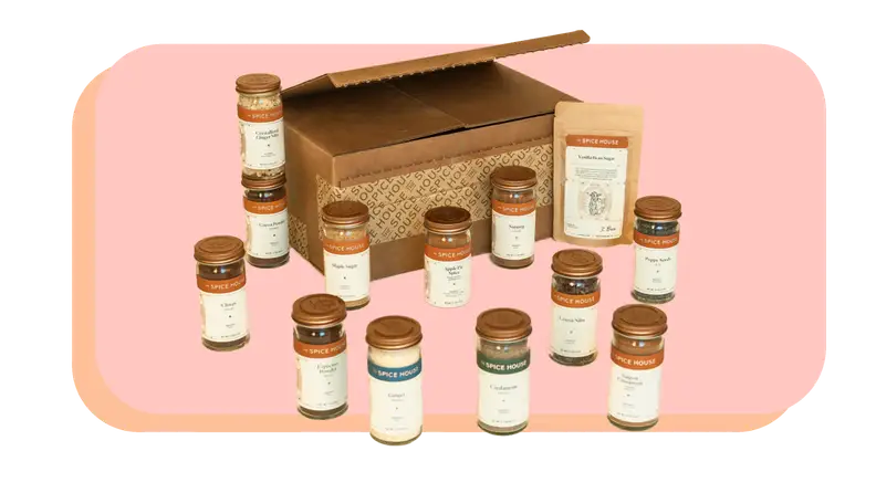 Twelve assorted spice jars next to cardboard box.