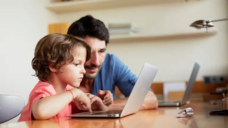 A parent and a child browsing on a laptop.