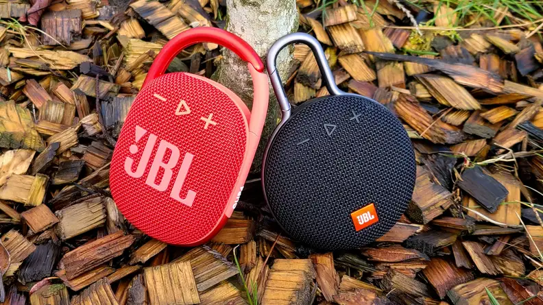 JBL Clip 4 and Clip 3 against tree on woodchips