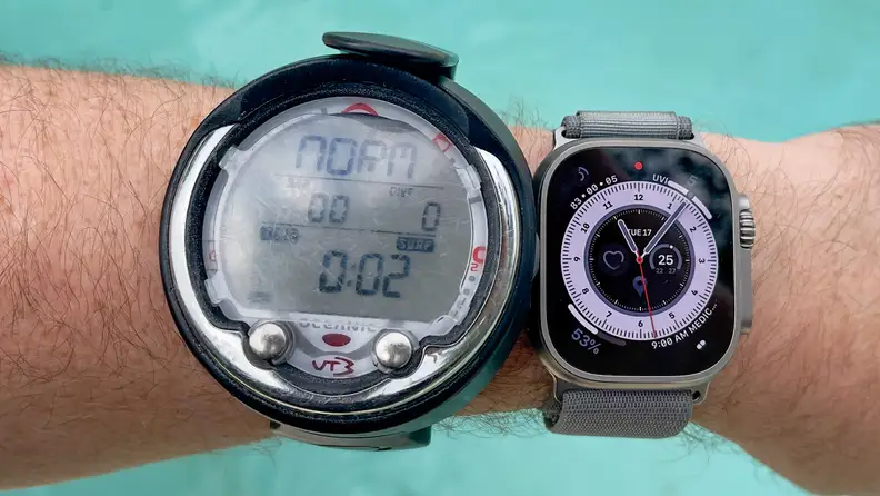 A diver wears an Oceanic dive computer and an Apple Watch Ultra, side-by-side, on the same arm