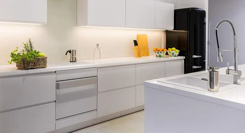 The Eve Light Strip displayed in the color white and installed under kitchen cabinets