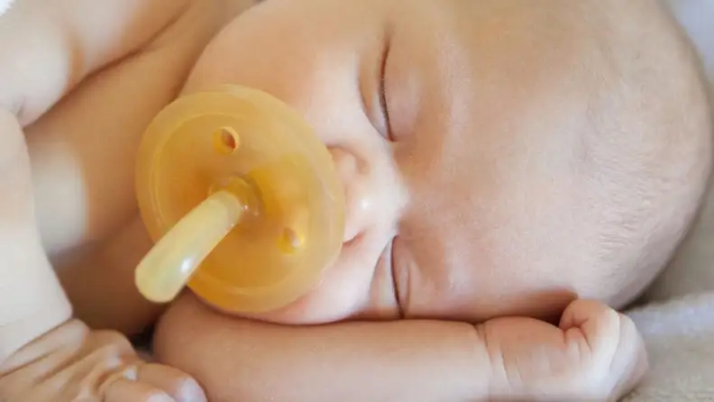 A sleeping baby with a very large Natursutten pacifier.