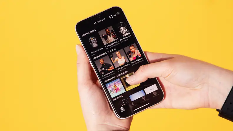 Person holding up smartphone featuring assorted fitness classes within the Liteboxer app.