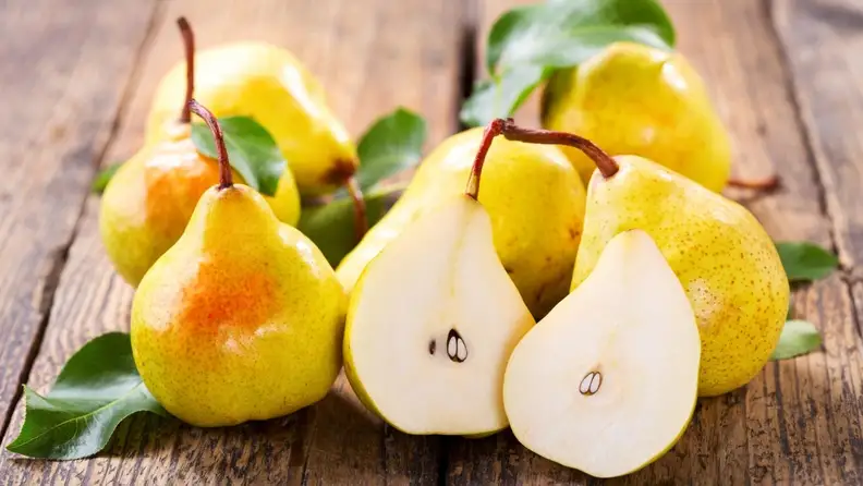 An image of 6 golden pears, one of which is sliced in half.