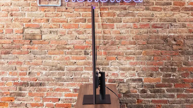 The side of the LG G4 OLED TV on a wood entertainment center and brick background.