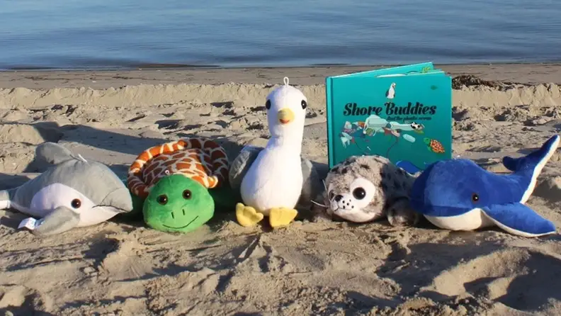 A line of marine-inspired stuffed animals sit on the beach