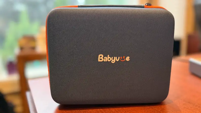 Black and orange travel case for the Babyvue BV6 Baby Car Monitor & Camera on a wooden table.