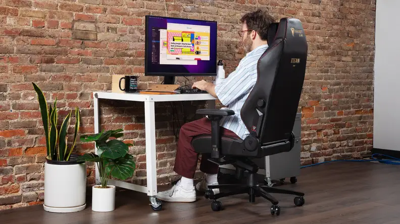 A person sitting on the chair interacting with a desktop.
