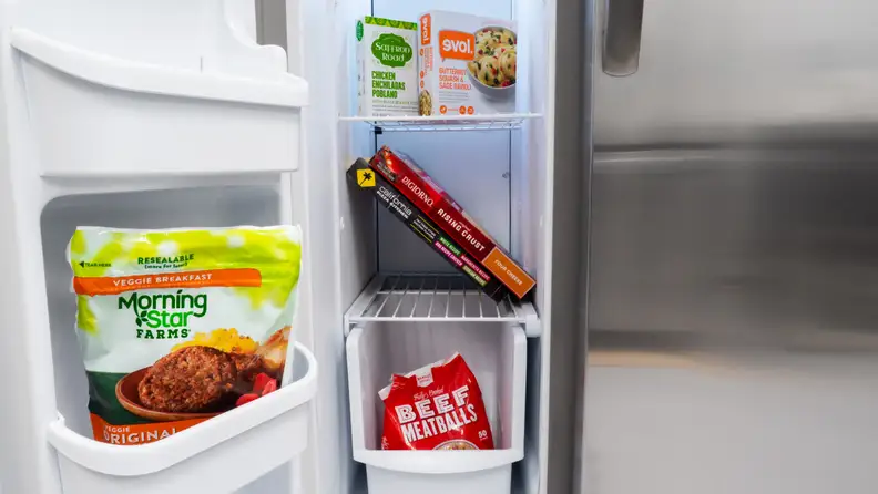 A close-up of the Frigidaire FFSS2315TS side-by-side refrigerator's freezer compartment, underneath its ice-maker, which takes up the top quarter of the total space.