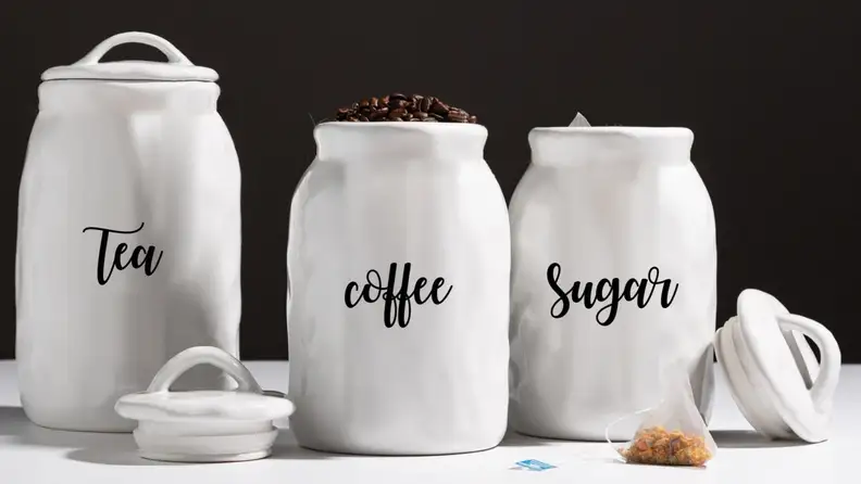 Three ceramic canisters that store tea, coffee, and sugar.