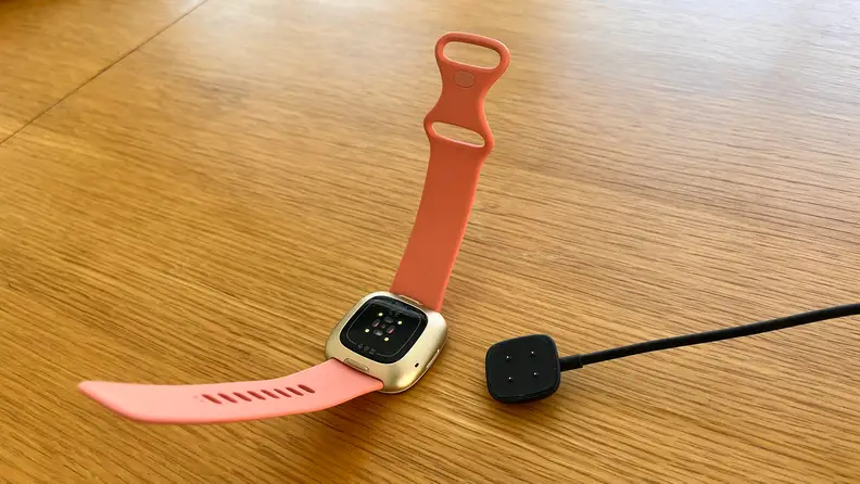 A smartwatch next to its magnetic charger