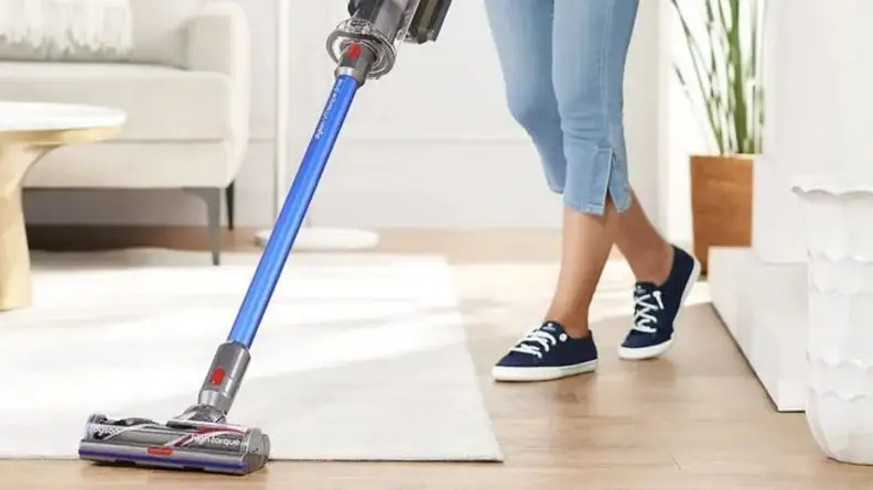 woman vacuuming white rug with Dyson vacuum