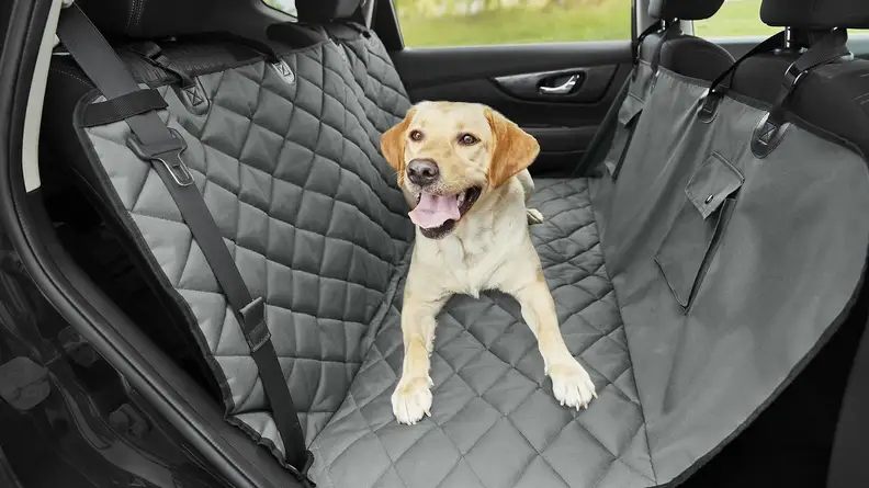 An image of a gray seat cover in a car with a dog sitting on it.