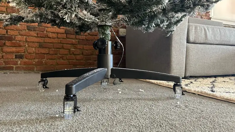 A black artificial Christmas tree stand with wheels.
