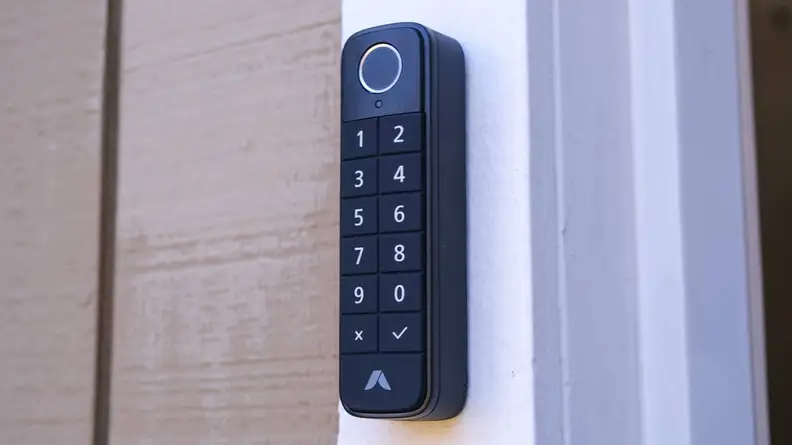 The Abode Lock keypad mounted on a white wood door frame outside.