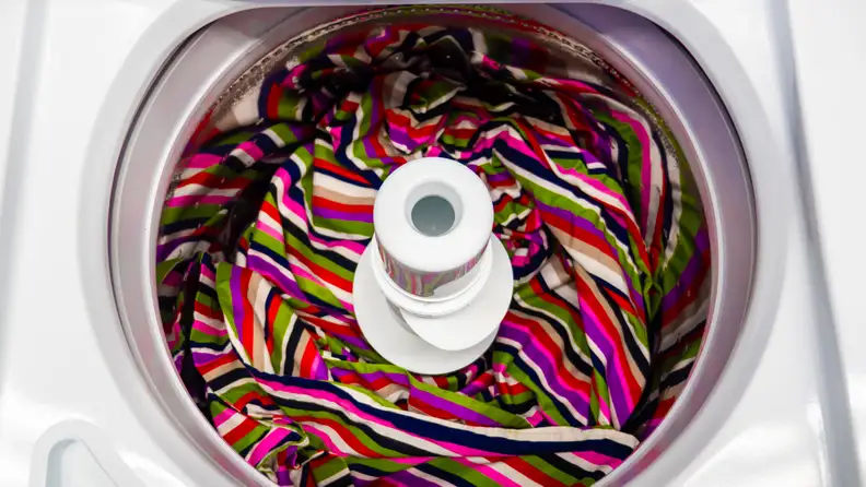 A top-down shot of the interior of the Maytag MVWP576KW Top-loading Washing Machine with Pole Agitator, with a colorful blanket placed in the drum.