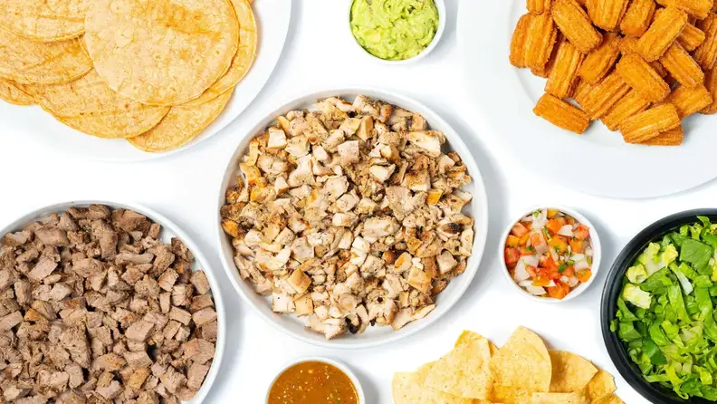 An overhead spread of taco fillings, including chicken, steak, chips, and guacamole