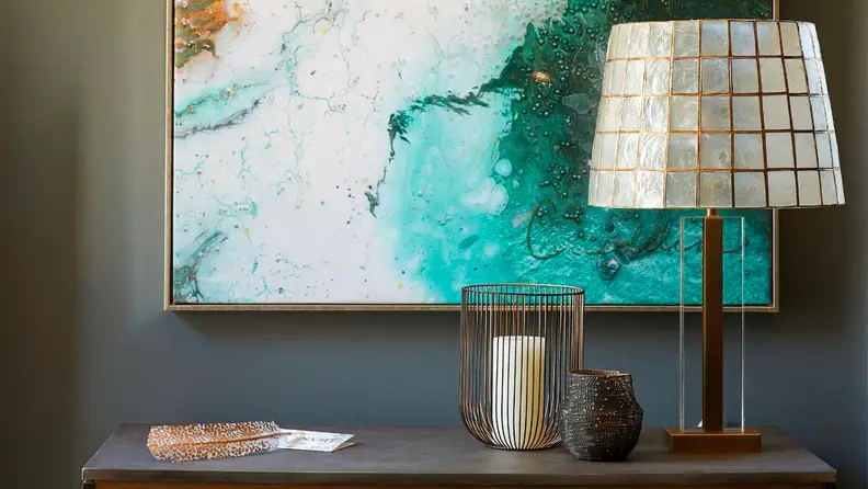 Close up of a credenza holding a lamp with a capiz shade.