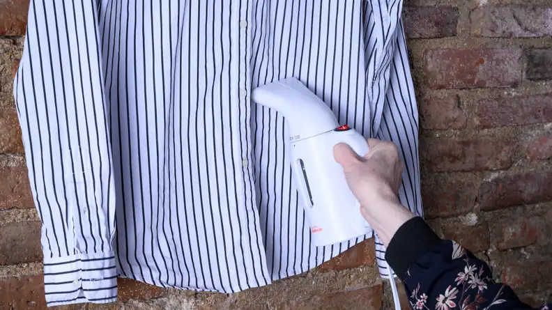 A hand-held steamer removing wrinkles from a cotton blouse
