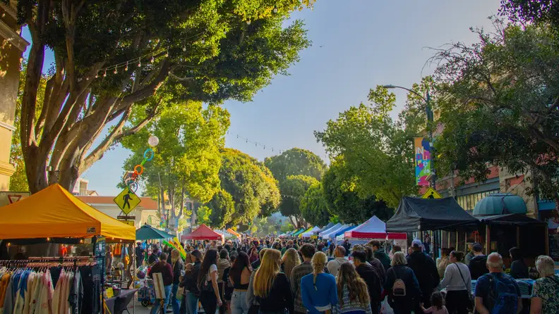Crowded street lined with market tents at dusk